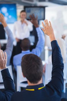 Rear view of Business people raising their hands in business seminar. International diverse corporate business partnership concept