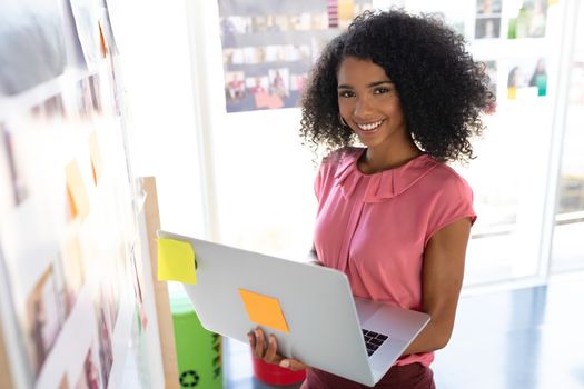 Portrait of happy African american female fashion designer using laptop in design studio. This is a casual creative start-up business office for a diverse team
