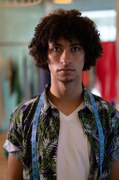 Portrait of young mixed race male fashion designer standing in design studio. This is a casual creative start-up business office for a diverse team