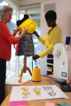 Close-up of sketch paper and thread spool on a table in design studio. This is a casual creative start-up business office for a diverse team