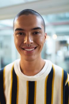 Portrait of mixed race male graphic designer smiling in office. This is a casual creative start-up business office for a diverse team