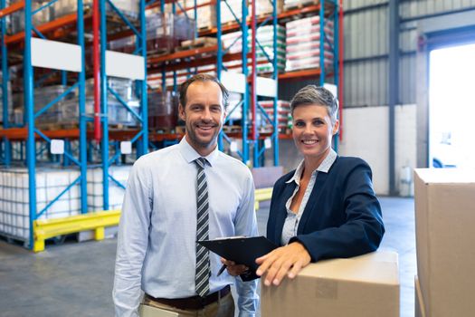 Portrait of happy Caucasian staffs looking at camera while working together in warehouse. This is a freight transportation and distribution warehouse. Industrial and industrial workers concept