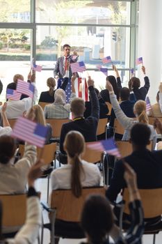 Front view of young Caucasian businessman doing speech and celebrating victory in conference room