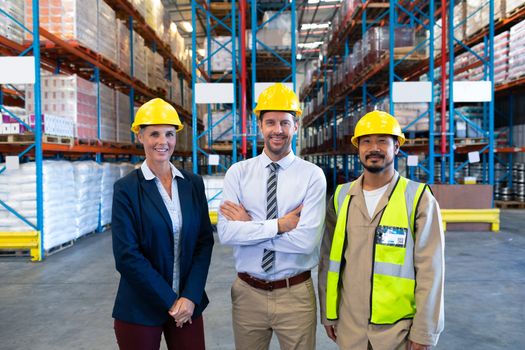 Front view of happy confident diverse staffs looking at camera in warehouse. This is a freight transportation and distribution warehouse. Industrial and industrial workers concept