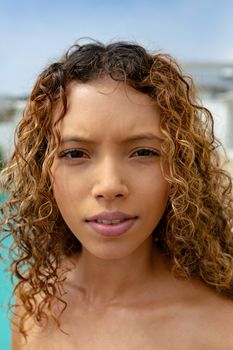 Close-up of beautiful mixed-race woman looking at camera. Summer fun at home by the swimming pool