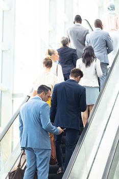 Rear view of diverse business people on escalator in modern office