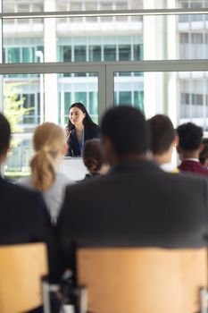 Front view of young Asian female executive doing speech in conference room