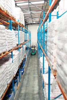 High angle view of African-american male worker driving forklift in warehouse. This is a freight transportation and distribution warehouse. Industrial and industrial workers concept