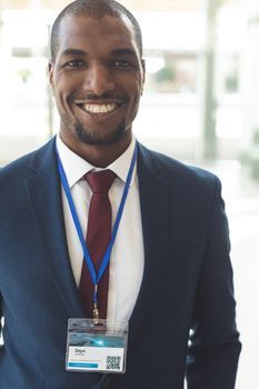 Front view of mature African-american businessman standing in empty conference room, smiling at camera