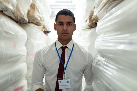 Portrait of handsome young Caucasian male supervisor looking at camera in warehouse. This is a freight transportation and distribution warehouse. Industrial and industrial workers concept