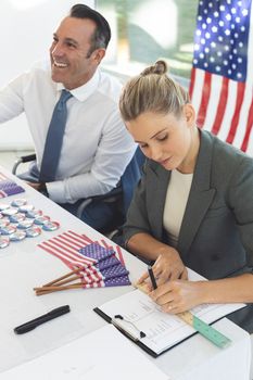 Front view of diverse business people sat next to desk, smiling and writing