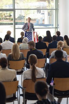 Front view of young Caucasian businessman doing speech in conference room