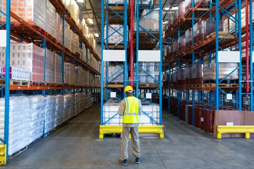 Rear view of African-american male worker working in warehouse. This is a freight transportation and distribution warehouse. Industrial and industrial workers concept