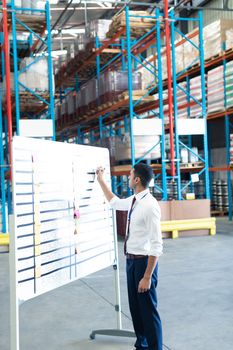 Side view of handsome young Caucasian male staff  writing on sticky notes in warehouse. This is a freight transportation and distribution warehouse. Industrial and industrial workers concept