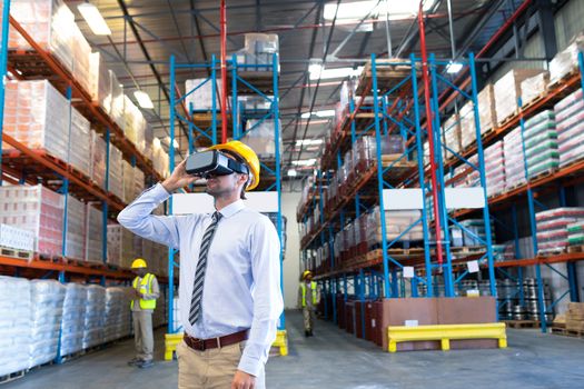 Front view of handsome mature Caucasian male supervisor using virtual reality headset in warehouse. This is a freight transportation and distribution warehouse. Industrial and industrial workers concept