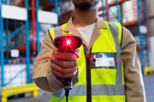 Mid section of mature Asian male worker showing barcode scanner on camera in warehouse. This is a freight transportation and distribution warehouse. Industrial and industrial workers concept