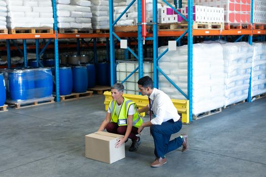 Front view of Young Caucasian male staff giving training to Caucasian female staff in warehouse. This is a freight transportation and distribution warehouse. Industrial and industrial workers concept
