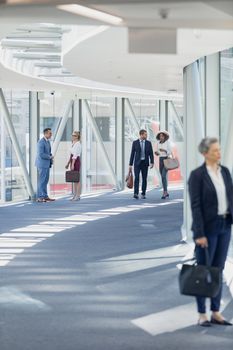 Front view of diverse business people walking in corridor in modern office