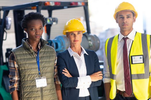 Front view of diverse warehouse staff looking at camera in warehouse. This is a freight transportation and distribution warehouse. Industrial and industrial workers concept