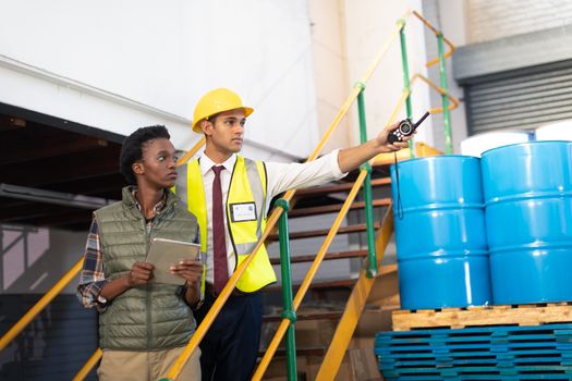 Front view of Caucasian male supervisor with African-american female worker pointing distance in warehouse. This is a freight transportation and distribution warehouse. Industrial and industrial workers concept