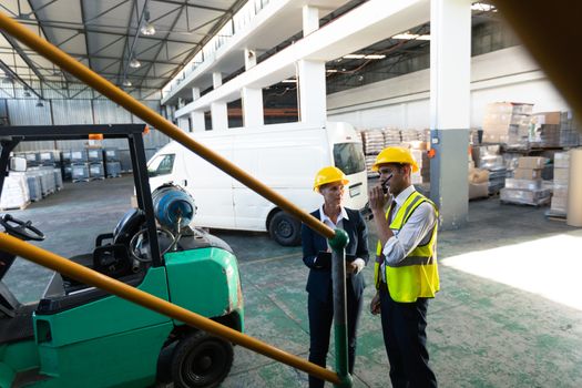 Front view of Caucasian female manager and Caucasian male supervisor working together in warehouse. This is a freight transportation and distribution warehouse. Industrial and industrial workers concept