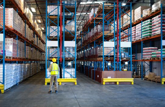 Rear view of African-american male worker working in warehouse. This is a freight transportation and distribution warehouse. Industrial and industrial workers concept