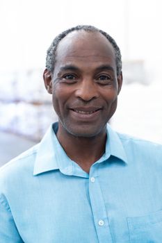 Portrait close-up of handsome mature African-american male supervisor looking at camera in warehouse. This is a freight transportation and distribution warehouse. Industrial and industrial workers concept
