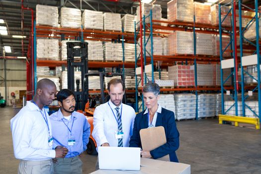 Front view of mature Caucasian warehouse staff discussing over laptop in warehouse. This is a freight transportation and distribution warehouse. Industrial and industrial workers concept