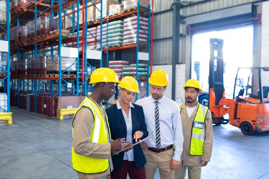 Front view of diverse staffs working together on clipboard in warehouse. This is a freight transportation and distribution warehouse. Industrial and industrial workers concept