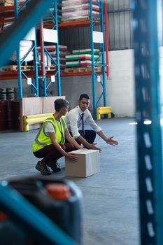 Side view of Young mixed-race male staff giving training to Caucasian female staff in warehouse. This is a freight transportation and distribution warehouse. Industrial and industrial workers concept