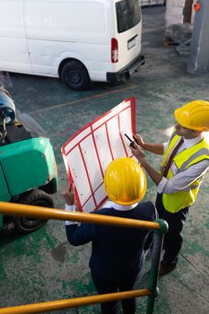 High angle view of Caucasian female manager and Caucasian male supervisor discussing over inventory chart in warehouse. This is a freight transportation and distribution warehouse. Industrial and industrial workers concept