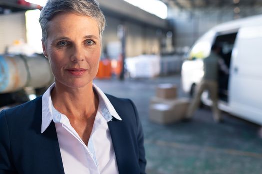 Portrait of happy Caucasian female manager looking at camera in warehouse. This is a freight transportation and distribution warehouse. Industrial and industrial workers concept