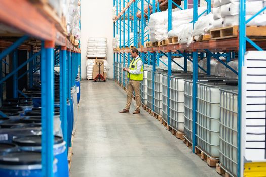 Side view of handsome Caucasian male worker standing in aisle in warehouse. This is a freight transportation and distribution warehouse. Industrial and industrial workers concept