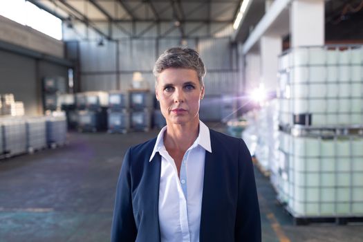 Portrait of Caucasian mature female manager standing in warehouse. This is a freight transportation and distribution warehouse. Industrial and industrial workers concept