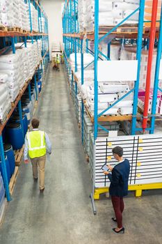 High angle view of diverse warehouse staff working together in warehouse. This is a freight transportation and distribution warehouse. Industrial and industrial workers concept