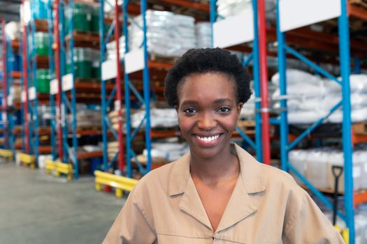 Portrait close-up of beautiful young African-american female staff looking at camera in warehouse. This is a freight transportation and distribution warehouse. Industrial and industrial workers concept