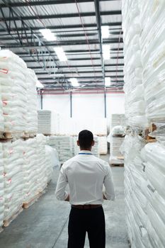 Rear view of thoughtful Caucasian male supervisor standing in warehouse. This is a freight transportation and distribution warehouse. Industrial and industrial workers concept