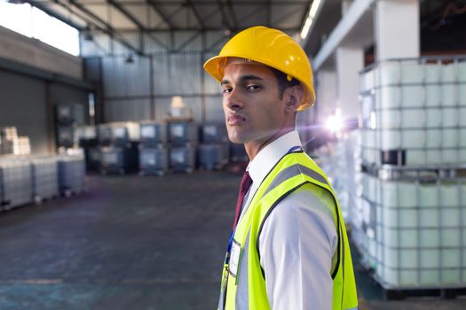 Portrait of African-american male staff in hardhat and reflective jacket standing in warehouse. This is a freight transportation and distribution warehouse. Industrial and industrial workers concept