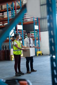 Side view of Caucasian Young male staff giving training to Caucasian female staff in warehouse. This is a freight transportation and distribution warehouse. Industrial and industrial workers concept