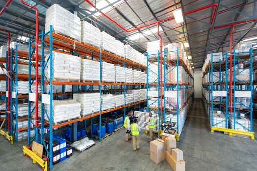 High angle view of diverse mature warehouse staff discussing over whiteboard in warehouse. This is a freight transportation and distribution warehouse. Industrial and industrial workers concept