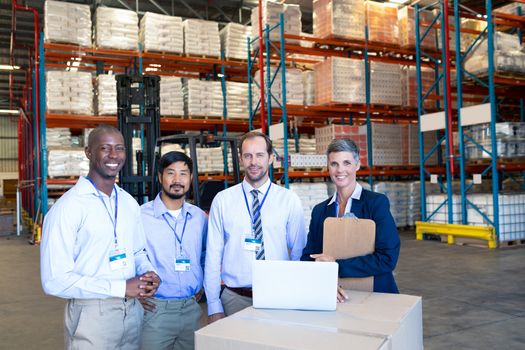 Front view of happy mature Caucasian staff looking at camera in warehouse. This is a freight transportation and distribution warehouse. Industrial and industrial workers concept