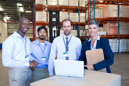 Front view of mature diverse staff looking at camera in warehouse. This is a freight transportation and distribution warehouse. Industrial and industrial workers concept