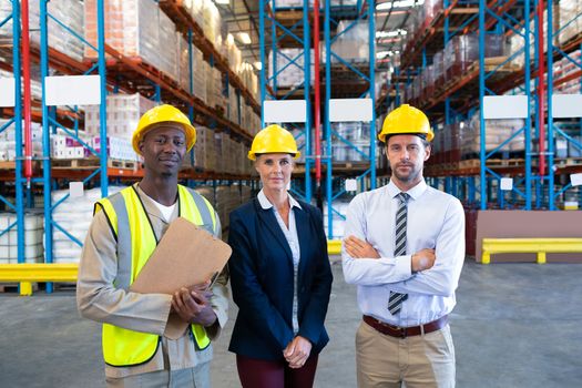 Front view of confident diverse staffs looking at camera in warehouse. This is a freight transportation and distribution warehouse. Industrial and industrial workers concept
