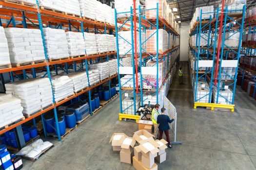 High angle view of mature Caucasian warehouse staff discussing over whiteboard in warehouse. This is a freight transportation and distribution warehouse. Industrial and industrial workers concept