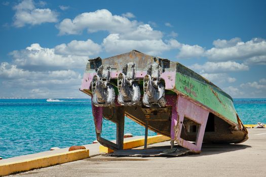 An old fishing boat with three outboard motors turned upside down on a pier