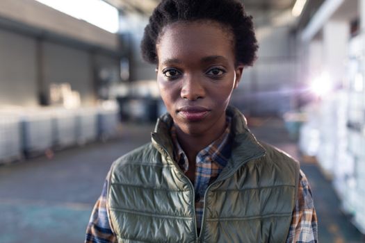 Close-up of African-american female staff standing with arms crossed in warehouse. This is a freight transportation and distribution warehouse. Industrial and industrial workers concept