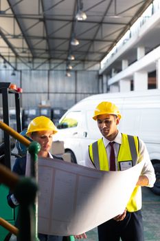 Front view of Caucasian female manager and Caucasian male supervisor discussing over inventory chart in warehouse. This is a freight transportation and distribution warehouse. Industrial and industrial workers concept