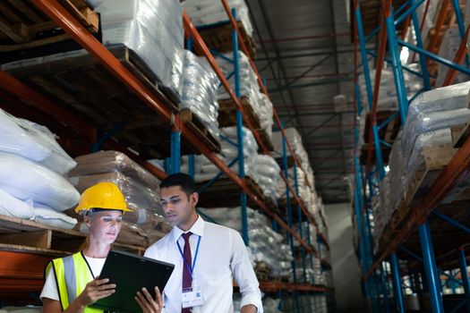 Front view of mixed-race Attentive male and female staffs discussing over digital tablet in warehouse. This is a freight transportation and distribution warehouse. Industrial and industrial workers concept