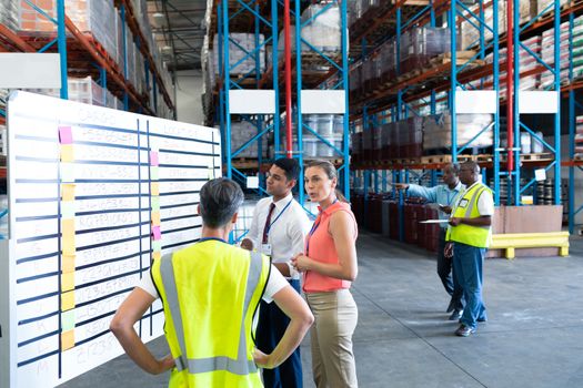 Front view of diverse warehouse staffs interacting with each other in warehouse. This is a freight transportation and distribution warehouse. Industrial and industrial workers concept
