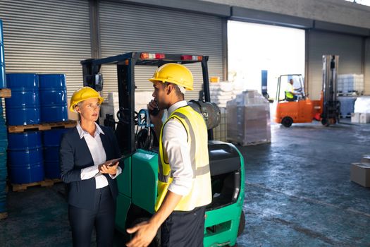 Front view of Caucasian female manager and male supervisor interacting with each other in warehouse. This is a freight transportation and distribution warehouse. Industrial and industrial workers concept